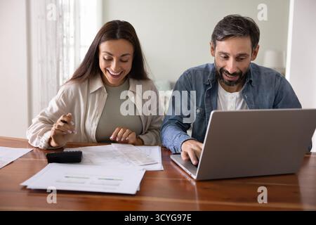 Friendly spouses busy with financial paperwork at home office desk Stock Photo