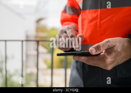 Closeup of hands of civil engineer using smartphone, selective focus Stock Photo