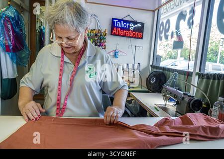 Miami Florida,Biscayne Boulevard business,tailor alterations shop inside interior,senior woman Hispanic female adult,using measuring tape and fabric o Stock Photo