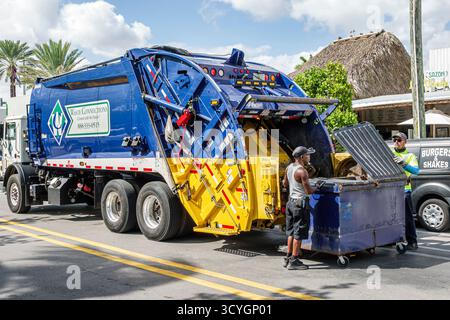 Miami Beach Florida,waste management garbage truck,Waste Connections company logo,trash collection commercial dumpster,Black male worker and Hispanic Stock Photo