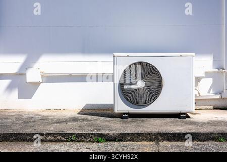 Air conditioner outdoor compressor unit on white wall with sunlight shadow, modern HVAC system concept for energy efficiency and home cooling technolo Stock Photo