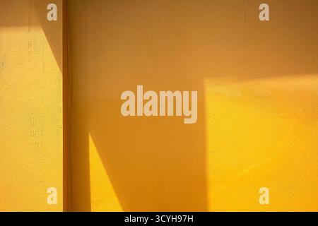Yellow wall with sunlight shadow, minimal abstract background showing geometric composition, modern simplicity, and bright energy for design and archi Stock Photo