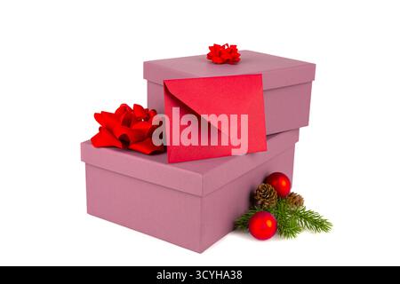 Christmas gift boxes with red ribbons, fir-tree branch with Christmas balls, cones and red envelope on white background. Two Christmas pink gift boxes Stock Photo