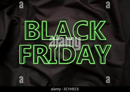 Black Friday sales, green neon lights  letters text on black silk cloth Stock Photo