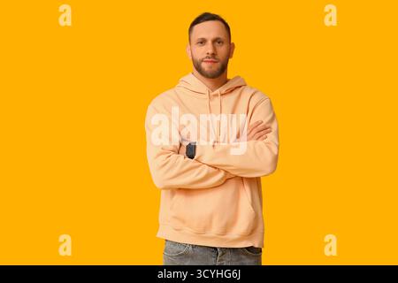 Stylish young man in hoodie on yellow background Stock Photo