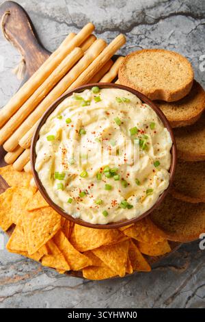 Tasty Deviled Egg Dip with nachos, breadsticks, and toast close-up in a plate on the table. Vertical top view from above Stock Photo