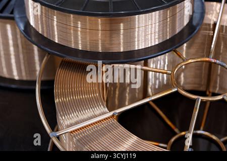 Spool with copper coated welding wire for semi-automatic welding machine, close-up shot, abstract background Stock Photo