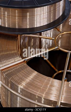 Spool with copper coated welding wire for semi-automatic welding machine, close-up shot, abstract background Stock Photo
