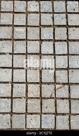 Close-up view of a square stone pavement with earthy joints and visible wear from outdoor exposure. Stock Photo