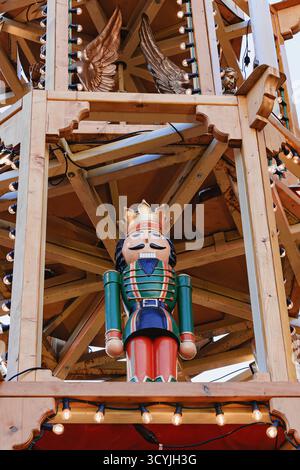 Cologne, Germany - December 12, 2022: Close-up of colorful Nutcracker figure with gold crown and lights on a wooden Christmas market tower during holi Stock Photo