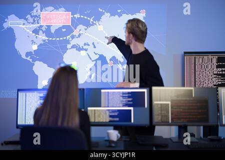 Team analyzing real-time cyber threats in a SOC environment using global dashboards Stock Photo