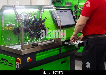 A car service engineer at the injector testing stand. Industry Stock Photo