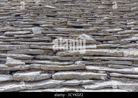Close-up view of a dry stone roof built from horizontal flat stones. The layered texture and weathered gray stones convey rustic charm, durability, an Stock Photo