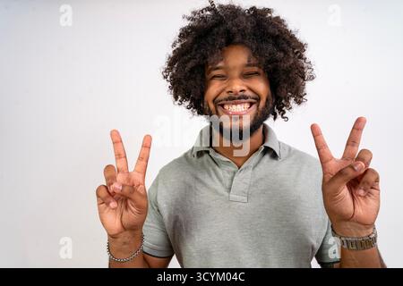 Happy young man showing peace sign with both hands smiling at camera Stock Photo