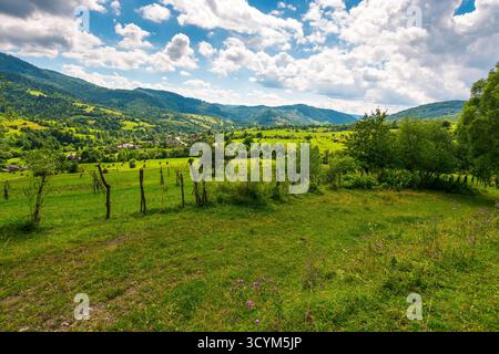 rural fields on rolling hills of ukraine in summer. wide angle countryside landscape of transcarpathia with stick fences in dappled light. uzhok villa Stock Photo