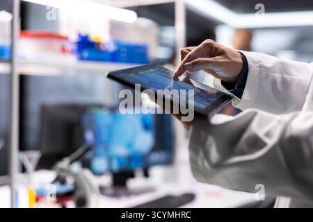 Close up of researcher in laboratory performing biochemistry on tablet, working on molecular testing. Healthcare data and laboratory equipment to advance diagnostics and medical discovery. Stock Photo