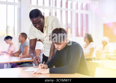 Professor explaining task solution to young man in college Stock Photo