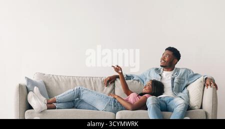 Young black woman switching on air conditioning at home Stock Photo