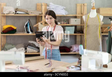 Woman dressmaker makes pattern using tablet Stock Photo
