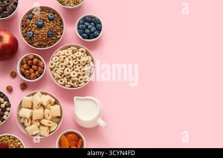 Bowls with different cereals and ingredients on pink background Stock Photo