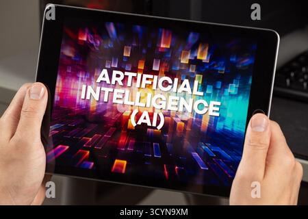 Close up to a male hands holding a digital tablet with the phrase artificial intelligence Ai over a hardware concept Stock Photo