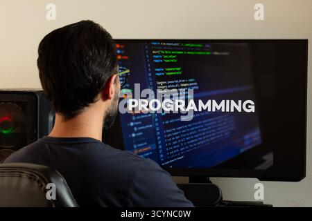 Close up to a man watching a computer screen with the word programming and a writting code concept Stock Photo