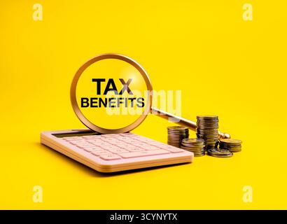 Tax benefit concept with magnifying glass highlighting the words “TAX BENEFITS” next to pink calculator and coin stacks on yellow background. Financia Stock Photo