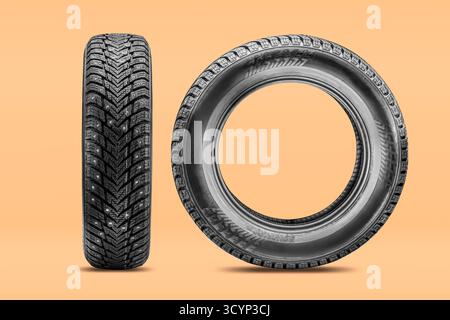 Two studded winter tires on a colored background. studded wheels for winter isolate concept. Winter tire replacement season. Stock Photo