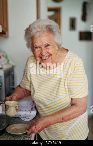 Elderly lady making coffee in coffee maker at morning. Stock Photo