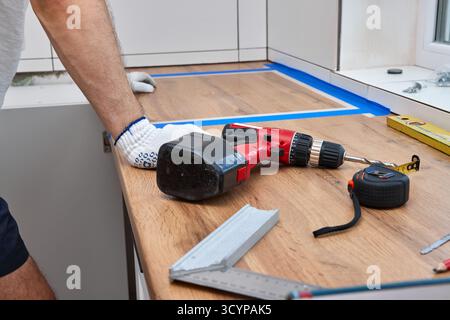 repairman working on a new kitchen installation and using electric drill Stock Photo