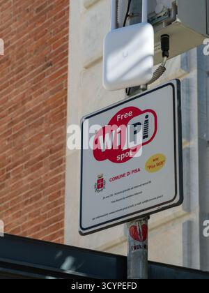 Free Wi-Fi spot sign promoting wireless internet access from Comune di Pisa, installed on a pole with an access point and a heart sticker, providing c Stock Photo