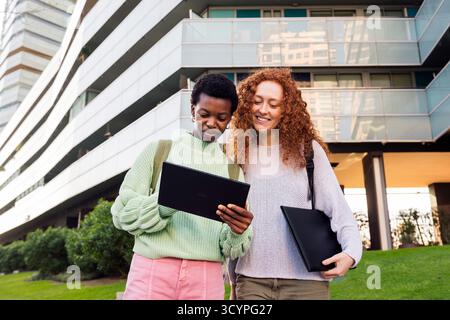 two young women smiling while using a tablet Stock Photo