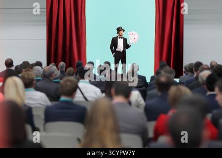 Magician performing on stage with playing cards Stock Photo