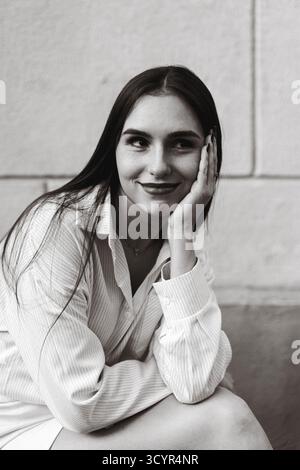 Portrait of young woman smiling while sitting thoughtfully Stock Photo