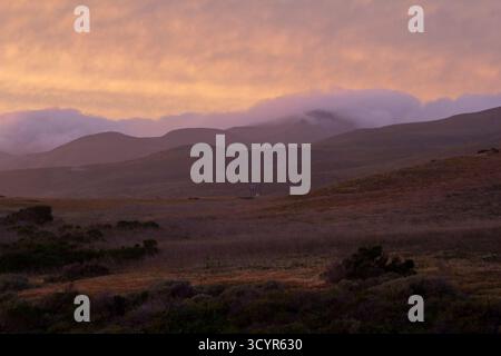 Soft pastel clouds rolling through open hill side. Stock Photo