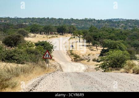 A steep donga or  dip; with road narrows sign on the C43 dirt road between Palmwag and Epupa Stock Photo