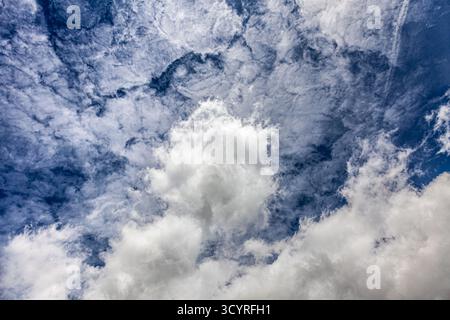 Dramatic sky with cumulus and cirrus clouds layered over a deep blue background—an atmospheric study in texture, contrast, and natural motion. Stock Photo