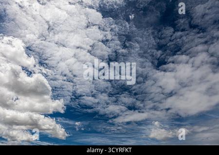 Dramatic sky with cumulus and cirrus clouds layered over a deep blue background—an atmospheric study in texture, contrast, and natural motion. Stock Photo