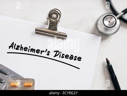 Medical report about alzheimer's disease with pills and stethoscope laying on doctor's desk Stock Photo