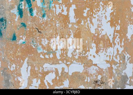 Aged wall with cracked surface and peeling white paint creating a weathered textured background. Stock Photo