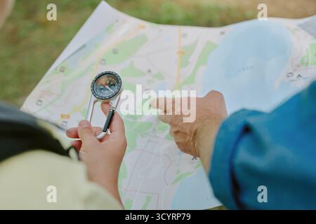 Young Adult Man Navigating Outdoors Using Compass and Paper Map Stock Photo