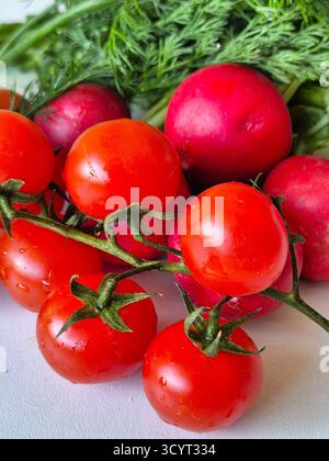 Fresh red cherry tomatoes, radishes, dill close-up. Stock Photo
