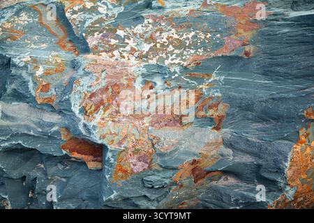 The texture of natural stone with an uneven surface and multi-colored inclusions Stock Photo