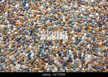 Bright small colored sea stones on gray sand, top view Stock Photo