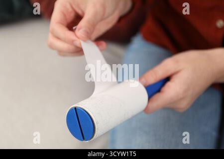 Woman removing sticky tape from lint roller at home, closeup Stock Photo