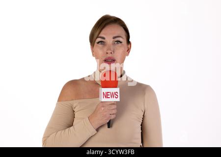 A female journalist is reporting the news, holding a microphone with a NEWS logo Stock Photo