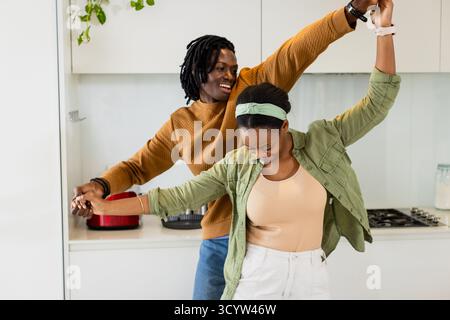 African American couple dancing together in modern home kitchen twirling near red toaster Stock Photo