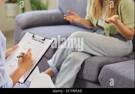 Therapist taking notes while patient gestures during supportive counseling session Stock Photo