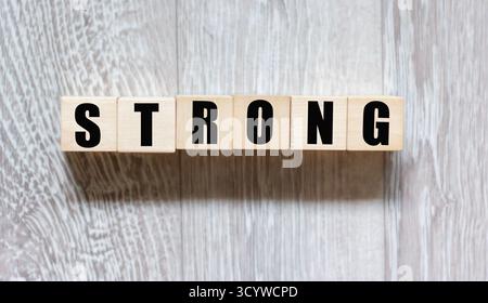 The word "strong" written in wooden letters on a gray background Stock Photo