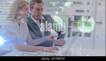 Collaborating two professionals analyzing figures at urban office, with laptop and digital overlays Stock Photo